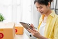 Startup small business, A young Asian woman checking online order on digital laptop and packing boxes for products. Royalty Free Stock Photo