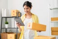 Startup small business, A young Asian woman checking online order on digital tablet and packing boxes for products. Royalty Free Stock Photo