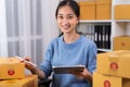 Startup small business, Young Asian women working digital tablet and checking box delivery products to customers, Ordered online.