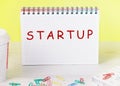 Startup - word concept on a checkered notebook on a yellow background
