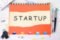 Startup - word concept on a piece of paper on an orange notebook