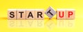 Startup word is made of wooden building blocks lying on the yellow table, concept Royalty Free Stock Photo