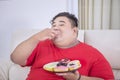 Starving fat man eating a plate of donuts at home