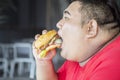 Starving obese man eating a big burger