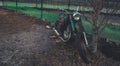 Stary Oskol, Russia January 25, 2019: Old rusty motorcycle near fence on ground. Close up of abandoned broken motorbike.