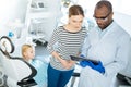 Pleasant dentist showing dental X-ray to mother of his patient Royalty Free Stock Photo