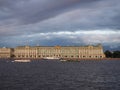 The State Hermitage Museum in St. Petersburg, with the touristic boats in front of it, on the background of dramatic stormy sky. Royalty Free Stock Photo