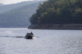 The state inspector is sailing in a motor boat along the reserved reservoir on a background of green hills