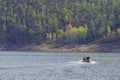 The state inspector is sailing in a motor boat along the reserved reservoir on a background of green hills