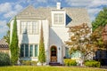 Stately Three story light colored stucco house with arched door and elegant trees framing windows