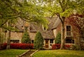 Stately upscale brick home framed by huge trees - landscaped with red azeleas and evergreen trees
