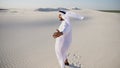 Happy Arabian UAE Sheikh man walks in middle of white desert and