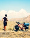 Static back view caucasian male cyclist standing by red touring bicycle looking to scenic mountains background. Active Royalty Free Stock Photo