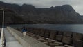 Static view from the drone on a young girl standing on a pier on a dark day. Agaete, Gran Canaria, Spain Royalty Free Stock Photo