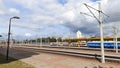 The station has laid tracks, tiled passing platforms, and power lines stretched out on concrete poles. A train of passenger railwa Royalty Free Stock Photo