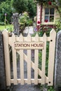 Station House sign on painted wooden gate leading. English country garden style scene