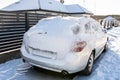 A station wagon car standing in front of a panel fence covered with ice and snow. Royalty Free Stock Photo