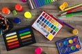 Stationary, flat lay top view of art workplace, wooden table with colored pencils, water colors and crayon pastel chalks Royalty Free Stock Photo