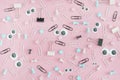 Stationery buttons, paperclips and asterisks in disorder on a pale pink background.Funny faces with puppet eyes and Royalty Free Stock Photo