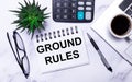 Stationery, a cup of coffee, a green plant and a notepad with the text BASIC RULES lie on a table with work lighting Royalty Free Stock Photo