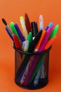 Stationery glass with felt-tip pens on an orange background