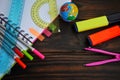 Stationery with a globe and markers spread out on a notebook lying on a dark wooden table, top viewn