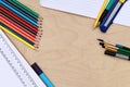 Stationery items on a wooden table. Composition of colored pencils, notebook, stationery knife, brushes, pens and marker Royalty Free Stock Photo