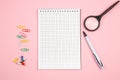 Stationery, paper notebook with pen and magnifier on pink isolated background. top view. flat lay. mockup