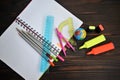 Stationery scattered on a notebook lying on a dark wooden table,