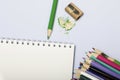 Stationery for school and teaching. Notepad and colored pencils for writing and drawing. Pencil sharpener with pencil shaving. Royalty Free Stock Photo