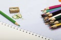 Stationery for school and teaching. Notepad and colored pencils for writing and drawing. Pencil sharpener with pencil shaving.