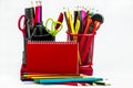 Stationery in two glasses, a red notebook, pencils isolated on a white background