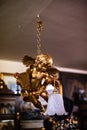 Statue of angel. Gold angel. A flower arrangement hanging from ceiling with lamp wooden background. On chain old vintage house