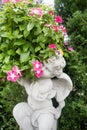 Statue of an angel holding a rose sitting on a tombstone in a ce