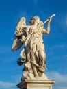 Statue of a holy angel with wings holding a war spear at the Saint Angel bridge on sky, Rome, Italy. Royalty Free Stock Photo