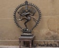 Statue of bronze indian godess in a circle against a sand coloured wall