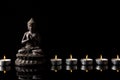 Statue of Buddha sitting in meditation, .candle line With black copy space . Zen and meditation concept