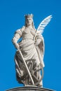 Statue of Catherin with writing bird feather, sword and cartwheel at ancient portal in Magdeburg, Germany, closeup, blue sky