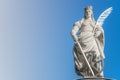 Statue of Catherin with writing bird feather, sword and cartwheel at ancient portal in Magdeburg, Germany, closeup, gradient blue