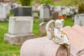 Statue of cherub holding a bird and sitting on a headstone