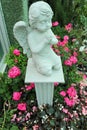 Statue child angle among pink flower. Royalty Free Stock Photo