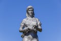 A statue of a collective farmer on a pedestal against a blue sky.