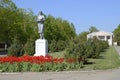 Statue of a collective farmer on a pedestal. The legacy of the Soviet era. A flower bed with tulips and young trees in