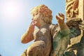 Statue of Cupid made of stone, a monument of love, glare from the sun, Funny overweight cupid aiming Royalty Free Stock Photo