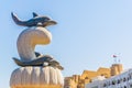 Statue of a dolphin on a Muttrah corniche with a fortress on background, Muscat, Oman