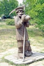 Statue of a farmer with scythe drinking from a jug