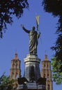 The statue of Father Miguel Hidalgo, framed by vegetation and the towers of the church