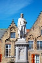 Statue of Hans Memling and medieval house exterior against blue sky in Brugge, Belguim Royalty Free Stock Photo