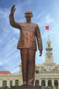 Statue of Ho Chi Minh with vietnamese flag in the background, in front of Saigon City Hall, Vietnam.