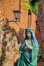 statue of the holy mother of God against the background of a brick wall of ivy-covered Royalty Free Stock Photo